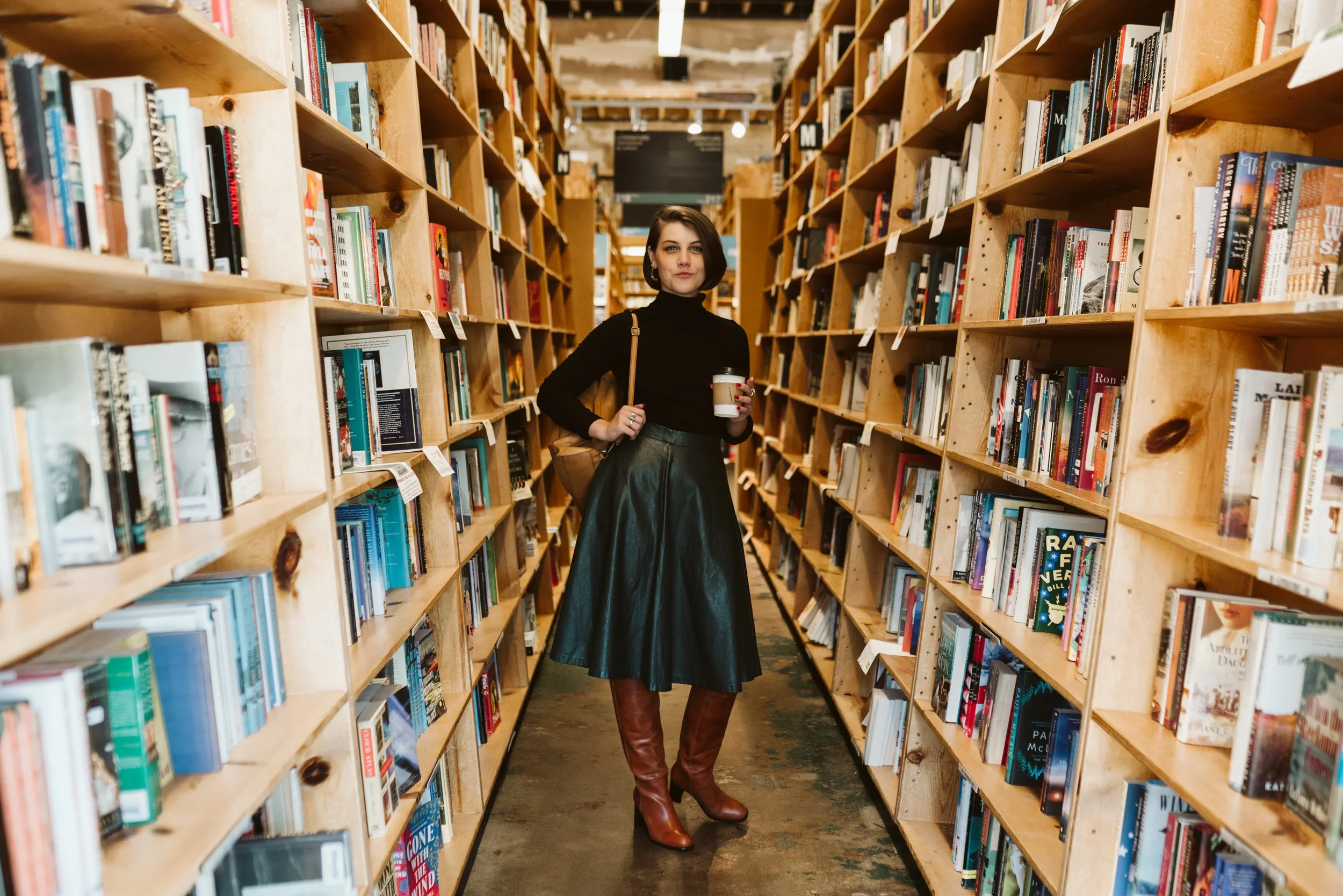 Meg stands in a bookstore aisle, coffee in hand, ready to roll.