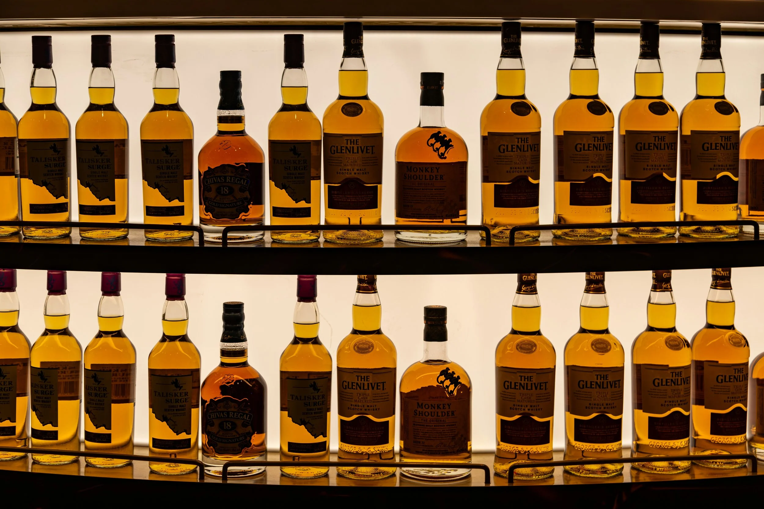 Bottles of whisky on shelves with labels such as Talisker, Chivas Regal, The Glenlivet, and Monkey Shoulder.