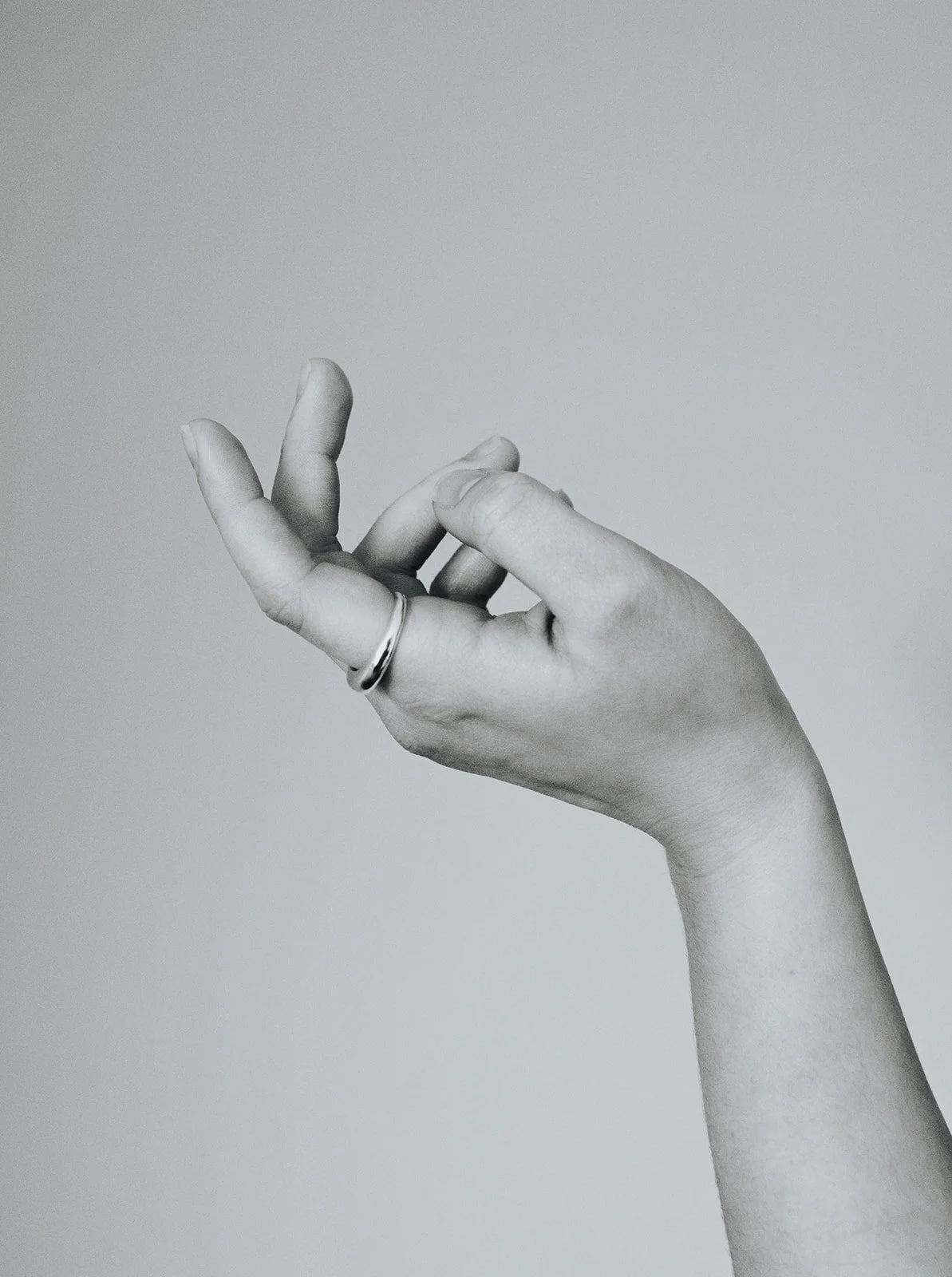 Two intertwined silver rings, one gold ring, and one black ring on a white background.