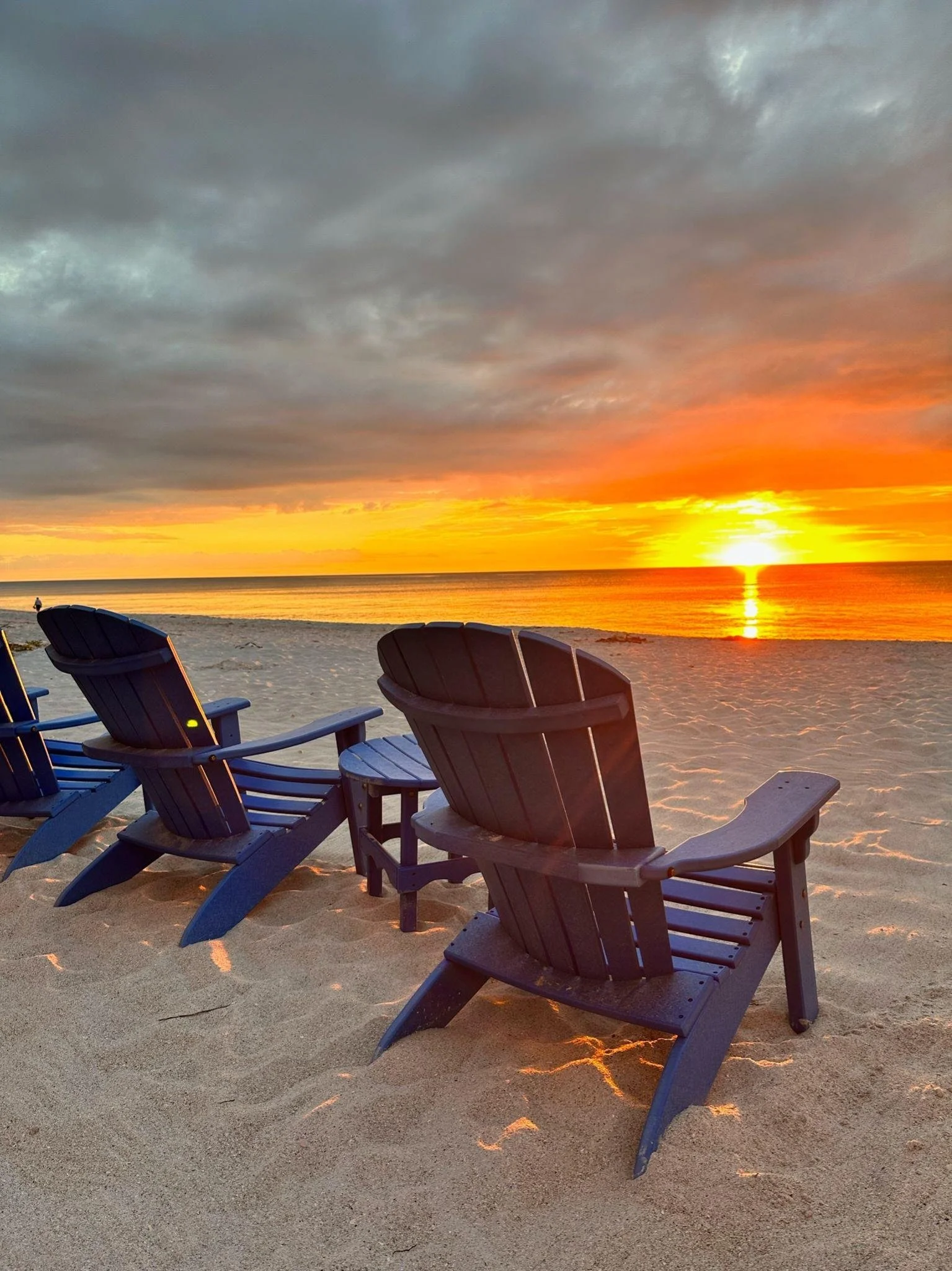 Two Adirondack chairs on the sand facing a Gulf of Mexico sunset on North Captiva Island