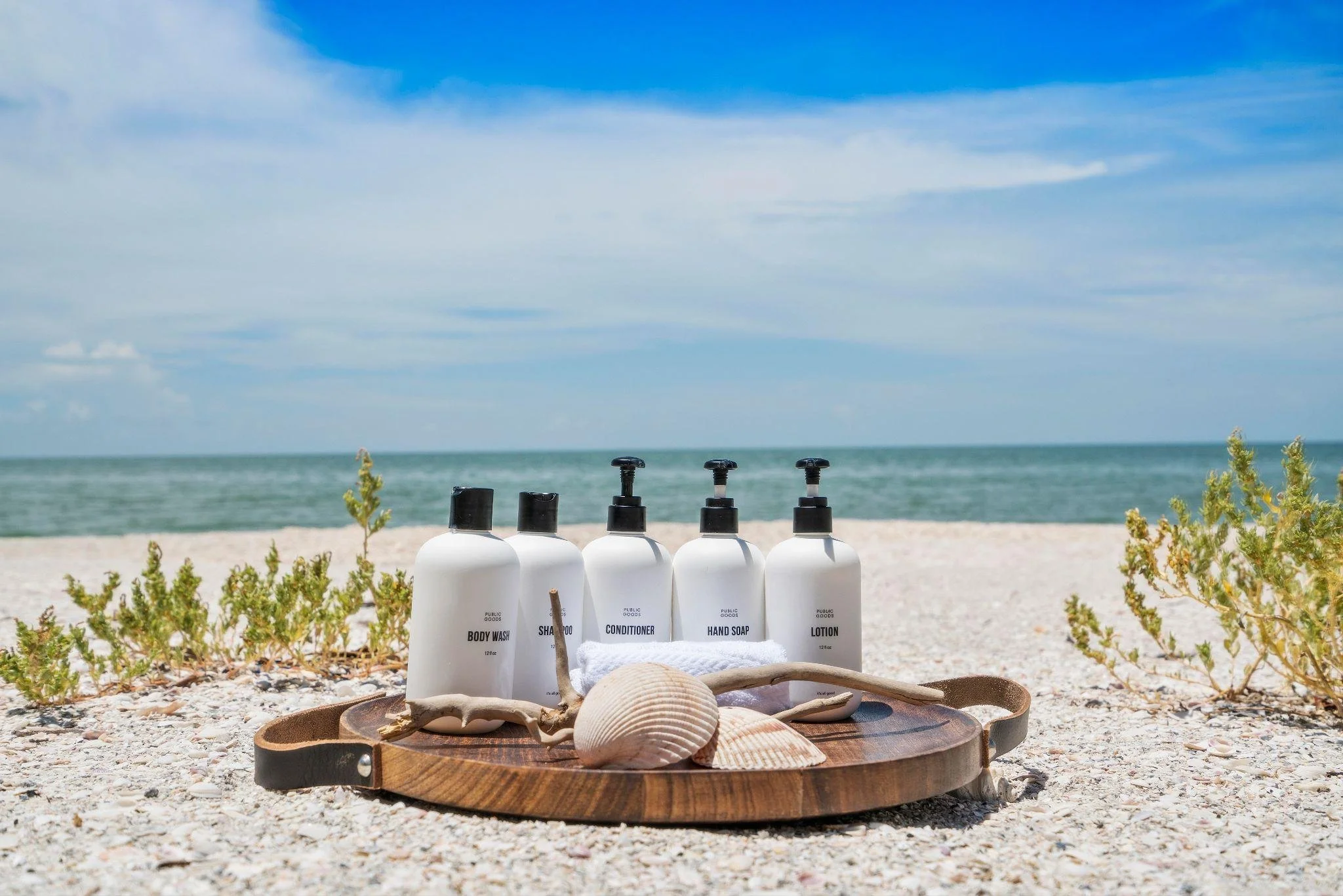 Vanage guest toiletries on a wooden tray with seashells on a North Captiva Island beach