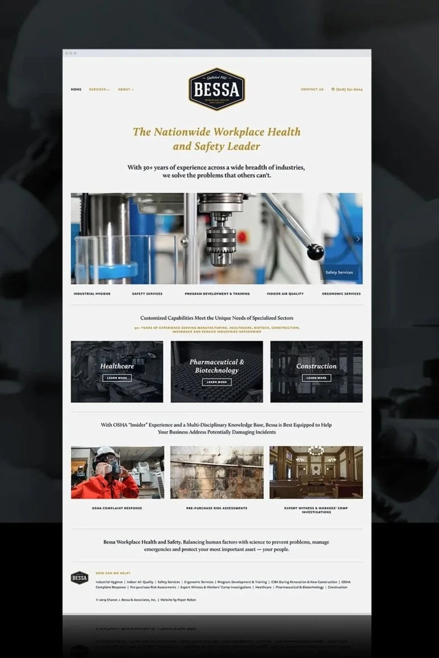 Website homepage for BESSA, a workplace health and safety company. Features navigation menu, logo, contact info, a hero image of machinery, and sections about services and industry sectors like healthcare, pharmaceuticals, biotechnology, and construction.