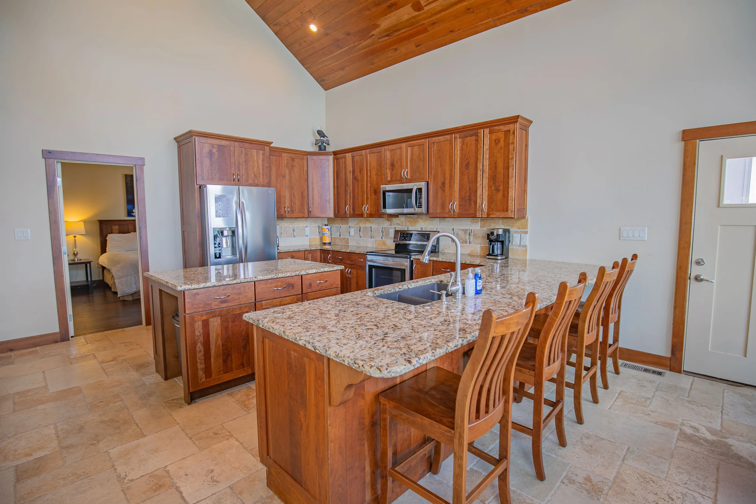 Kitchen with wooden cabinets, granite countertops, stainless steel appliances, a wall clock, and a decorative rooster figure on top of the cabinets.