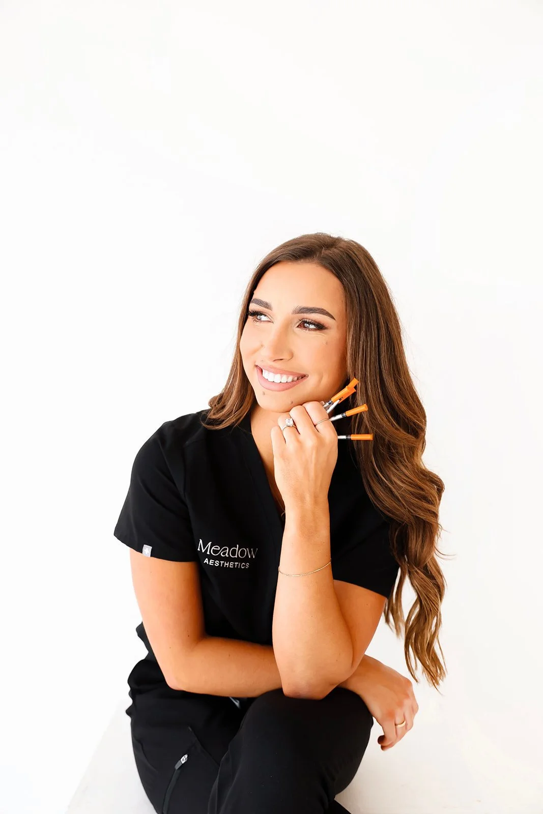 Addison, nurse injector at Meadow Aesthetics in Wichita, KS, holding syringes to promote tox treatments.