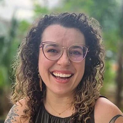 Shelby Hancock is a woman with brown curly hair wearing large glasses