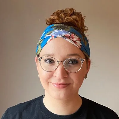 Emily Wilson is a white woman with round glasses and hair tied up with a bandana