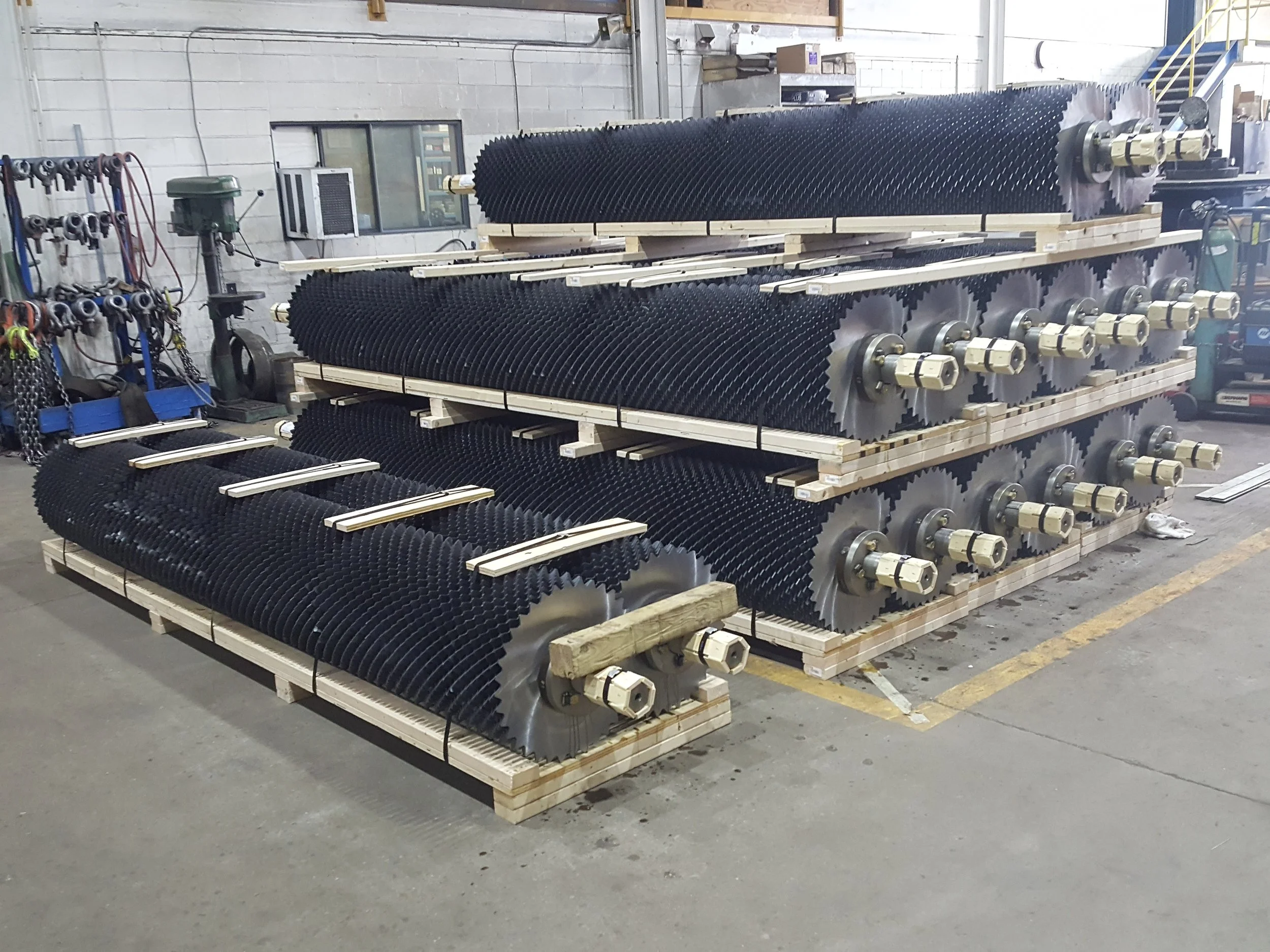 Industrial equipment with black conical blades arranged in multiple layers on wooden pallets in a warehouse.