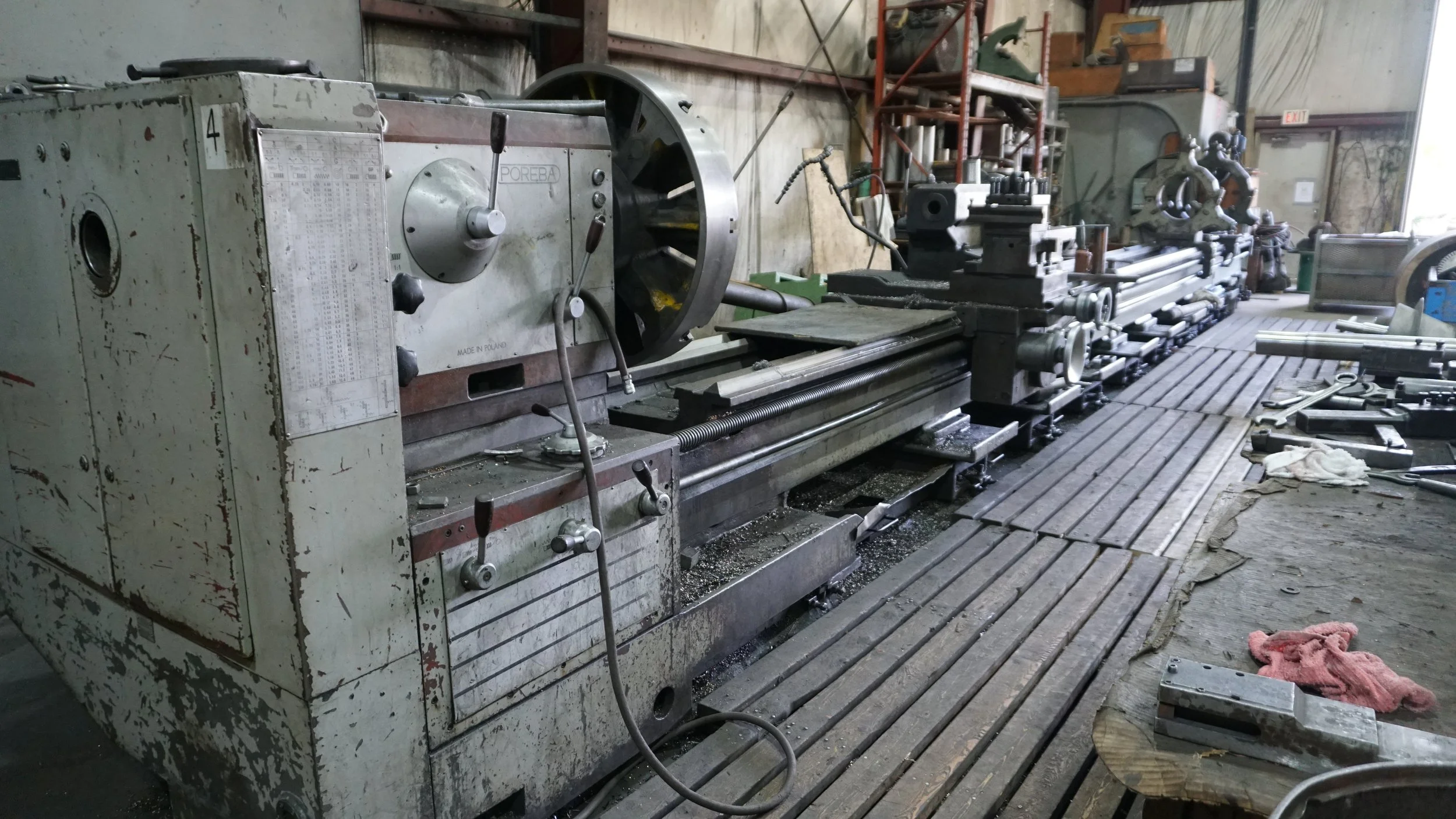 Sunrise Engineering - An industrial metal lathe machine in a workshop surrounded by tools, workpieces, and machinery.