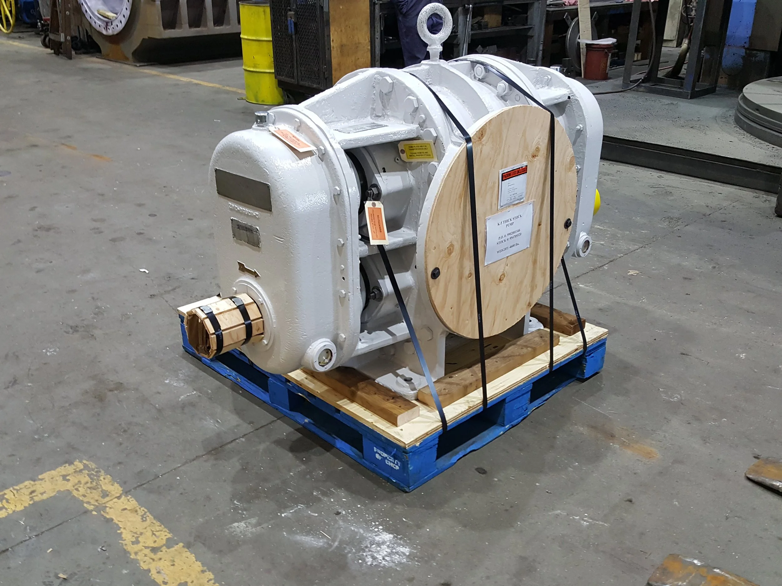 Sunrise Engineering - industrial pump with white exterior, mounted on a wooden pallet in a warehouse.