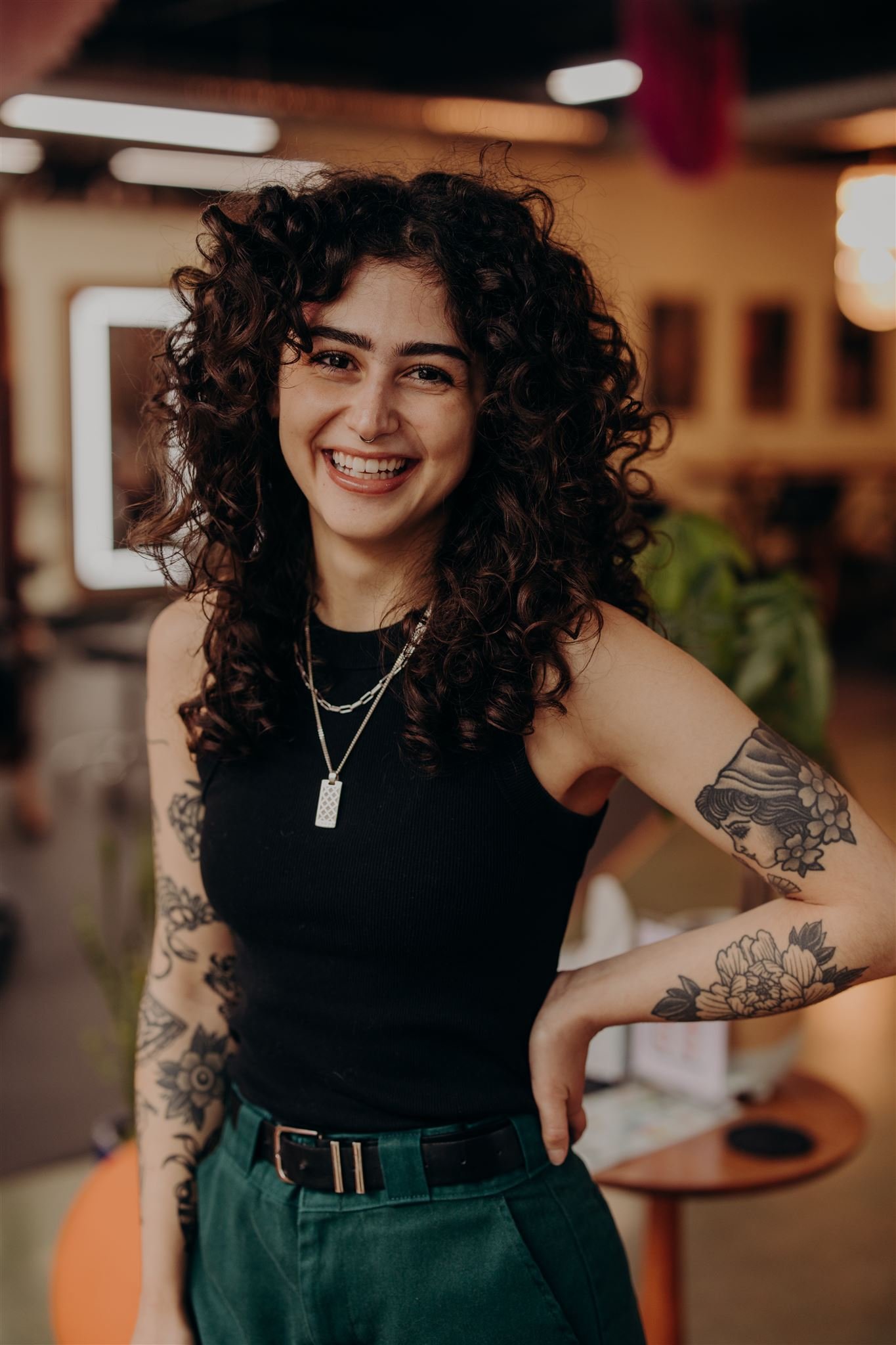 A young woman with curly dark hair, wearing a gray cropped T-shirt with