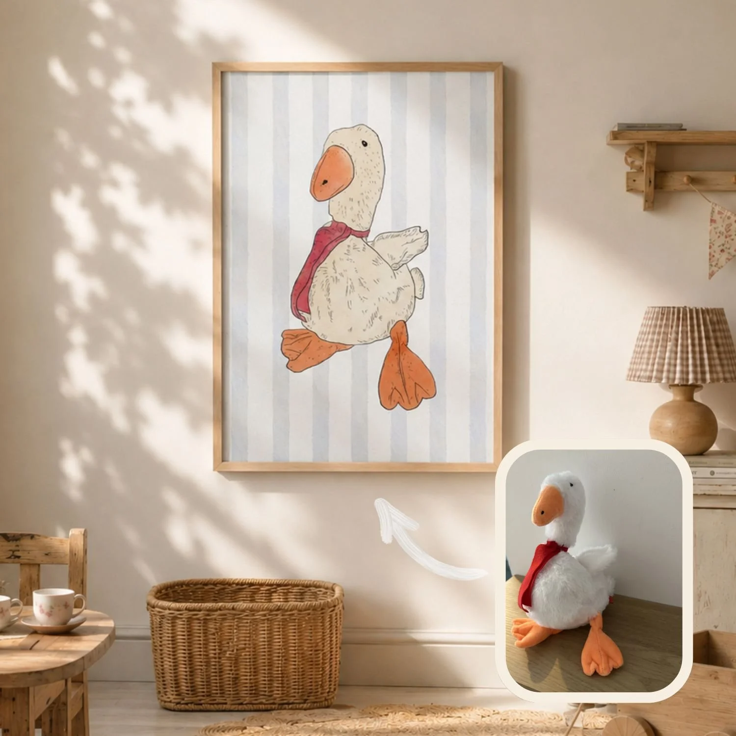 A framed illustration of a duck wearing a red scarf hangs on a beige wall, with a wicker basket, a wooden chair, and a table set with cups nearby. A plush duck toy with a red scarf is on a shelf to the right.