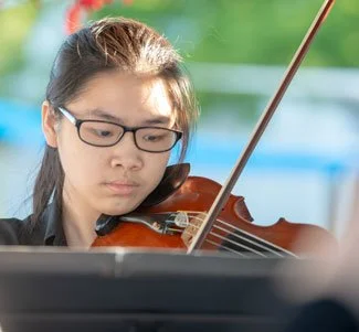 Young woman with glasses playing the violin