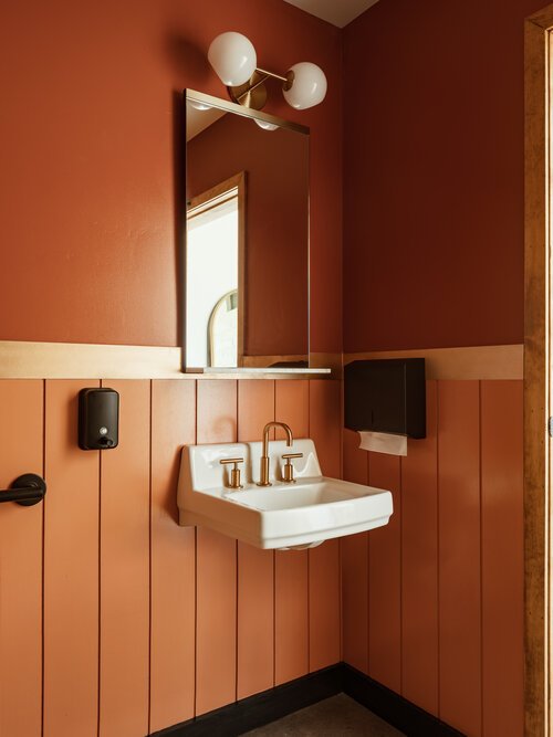  Modern, warm-toned bathroom at Greenwood Brewing with gold finishes.  