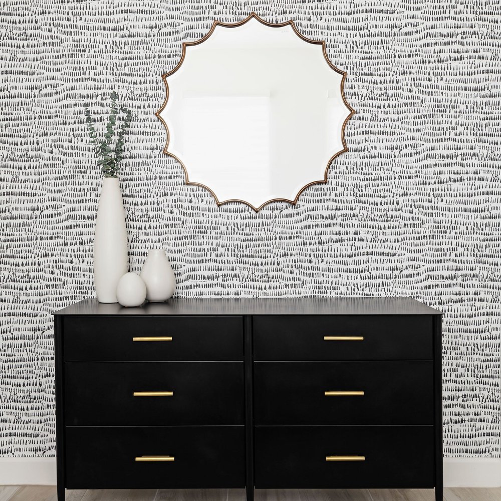  Black dresser, round scalloped mirror, and black and white accent wall. 