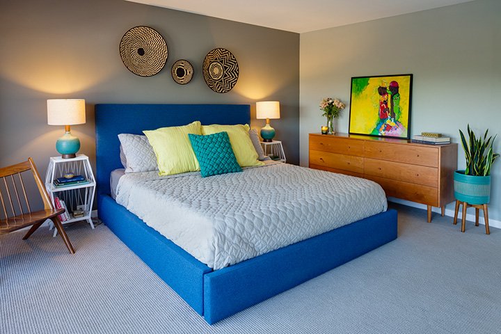 Collective mid century modern bedroom design with a minimalist, six-drawer dresser, abstract art, potted plants, and a Scandinavian accent chair.