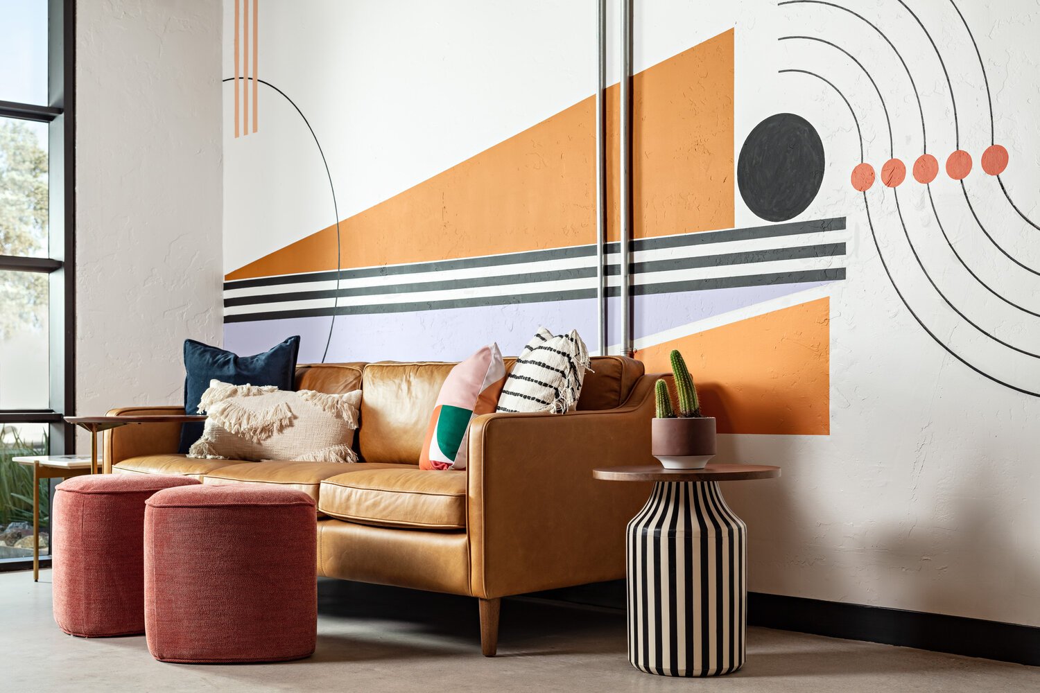 A leather sofa backs up to a custom wall mural in the mid century modern Lemonade Insurance office.