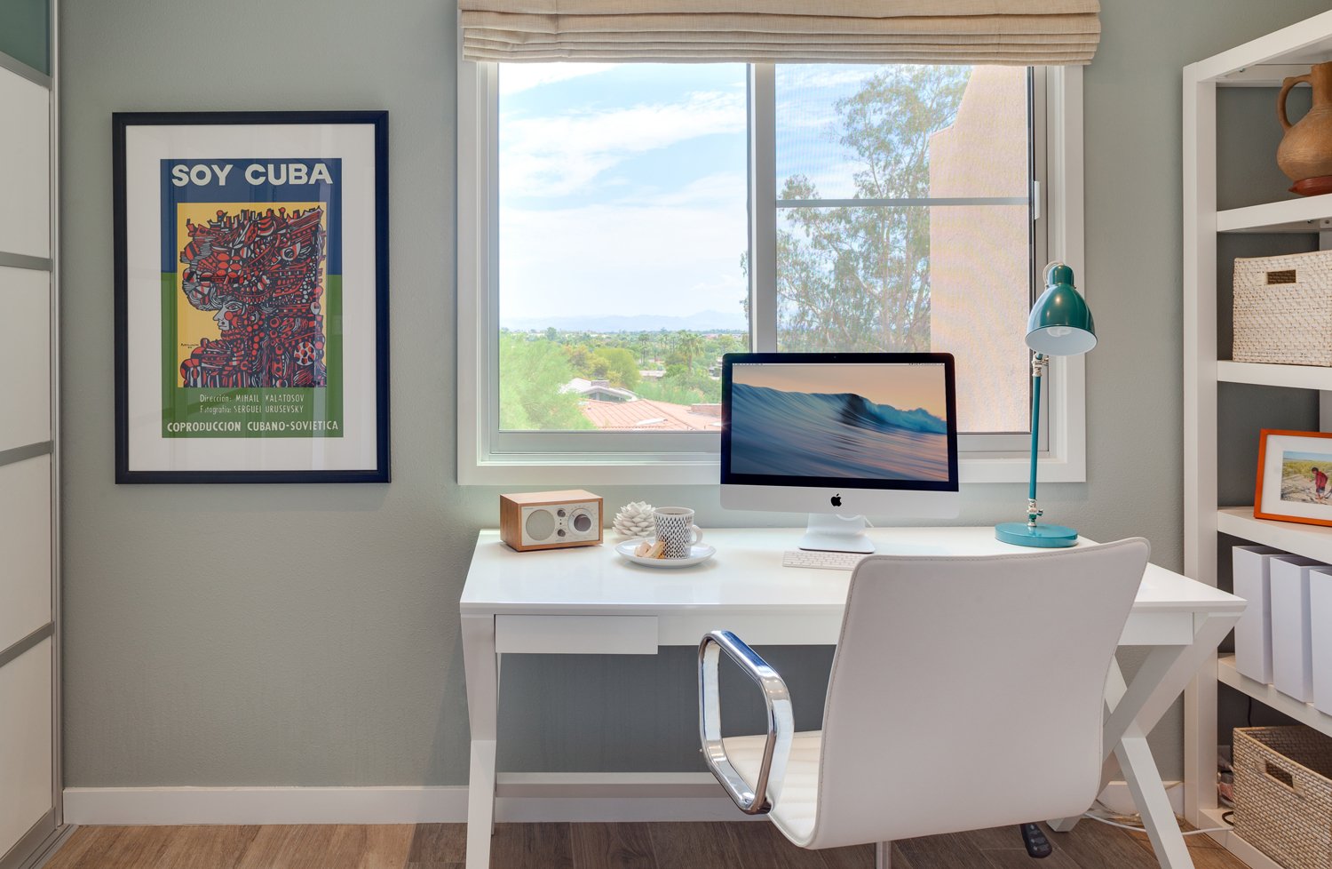 Modern home office in a Paradise Valley remodel with a white desk, custom shelving, colorful Cuban artwork and mountain views.
