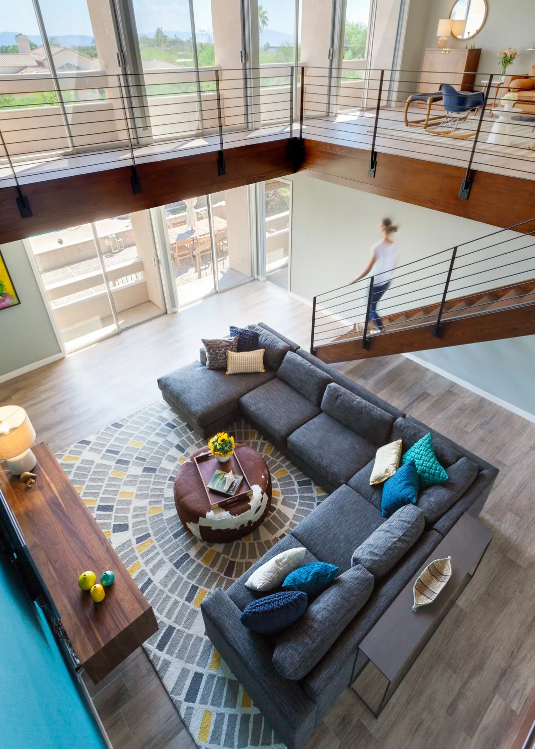 Open-concept Paradise Valley living room with a gray sectional, colorful accents, modern steel staircase and expansive mountain views.
