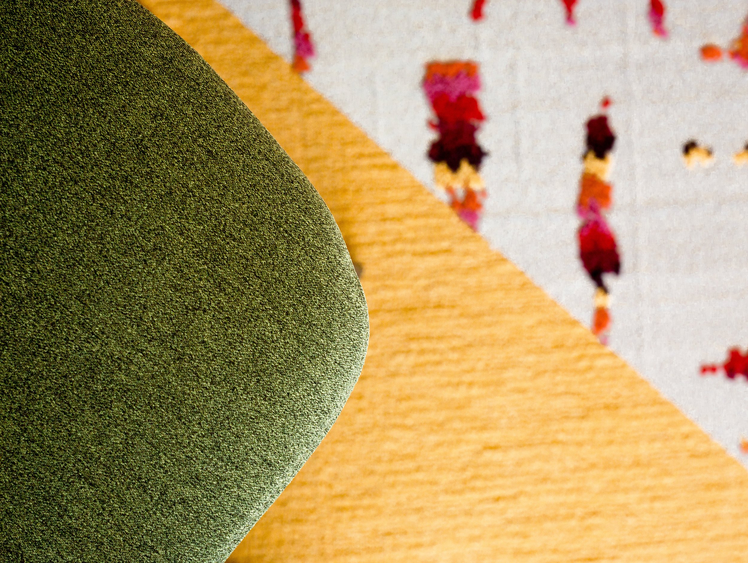 Green fabric of a dining chair against a colorful, patterned area rug.