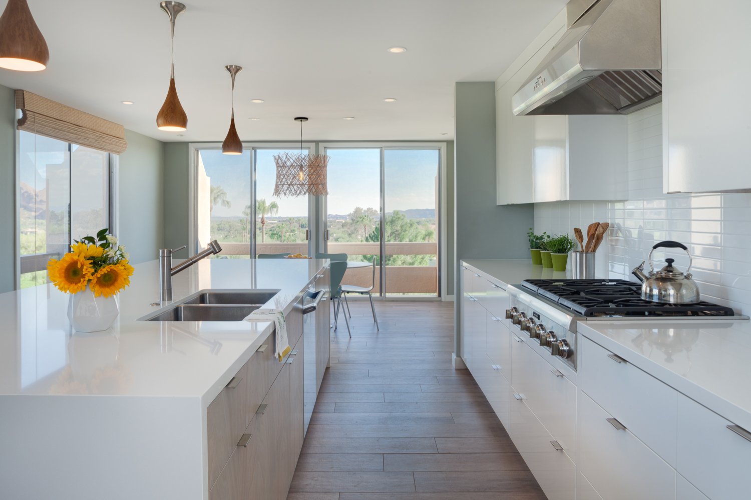 Mid-century modern kitchen remodel in Paradise Valley with white cabinetry, a large waterfall island, subway tile and wood pendant lights.