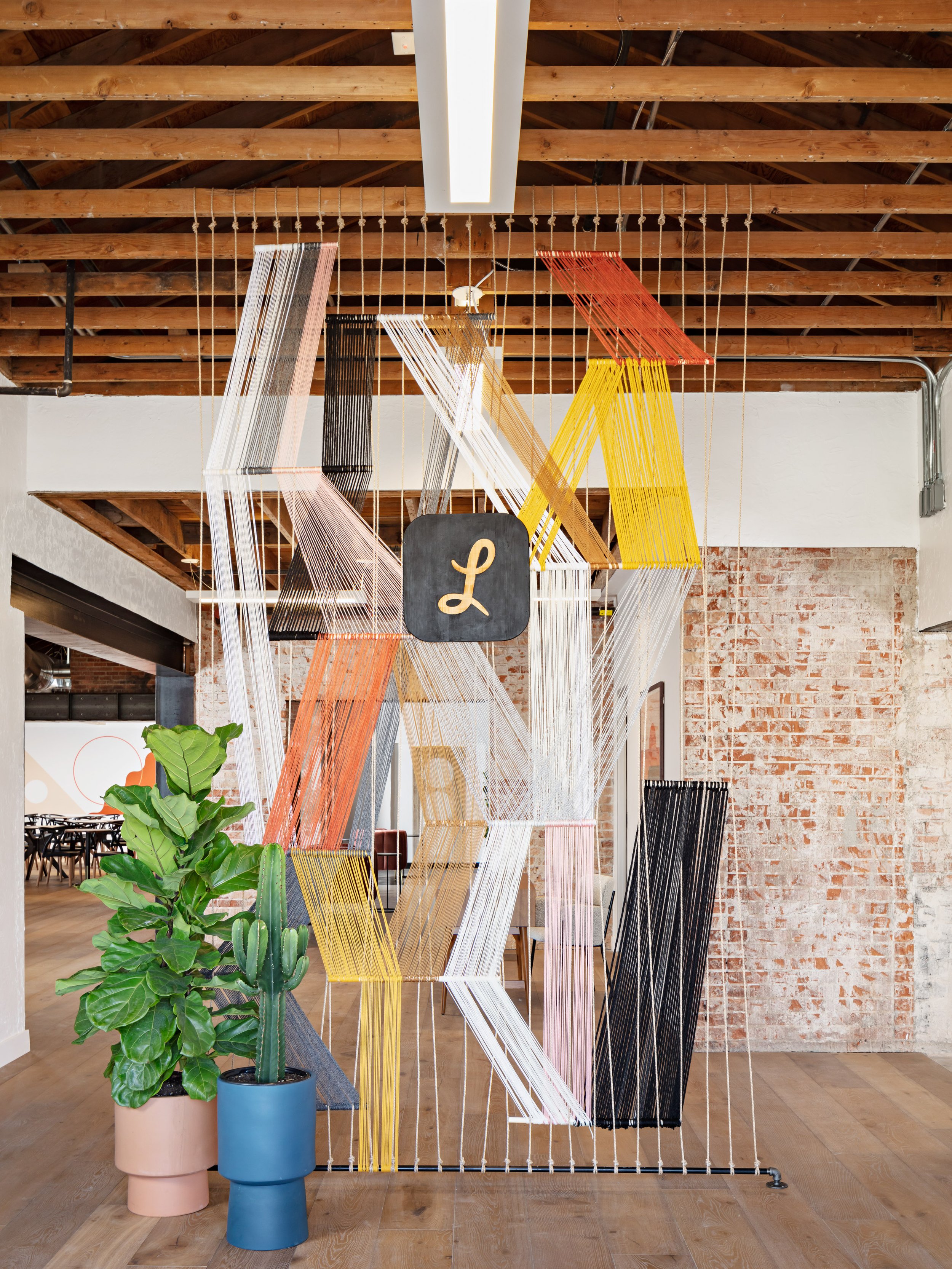 Custom art hangs from an exposed beam ceiling at Lemonade Insurance of Scottsdale's resimercial office.