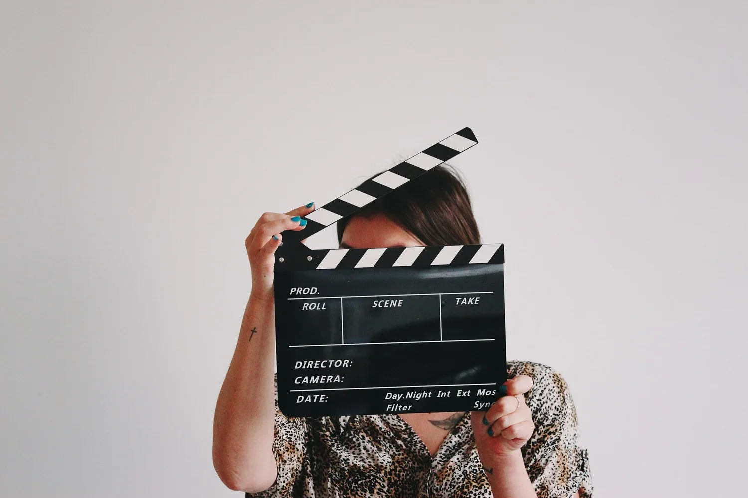 A person holding up a slate and covering their face.