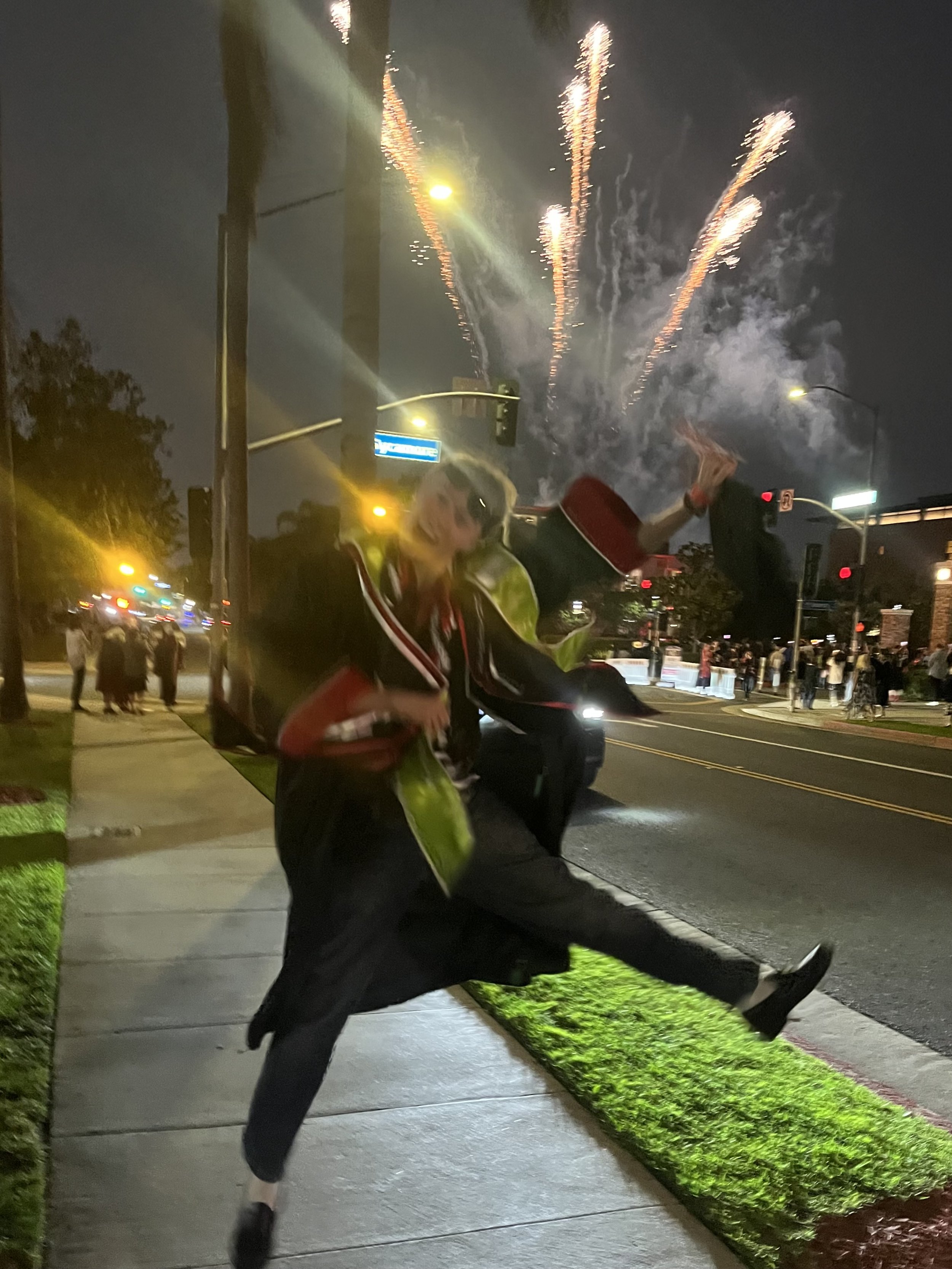 a boy jumping up with fireworks going off behind him