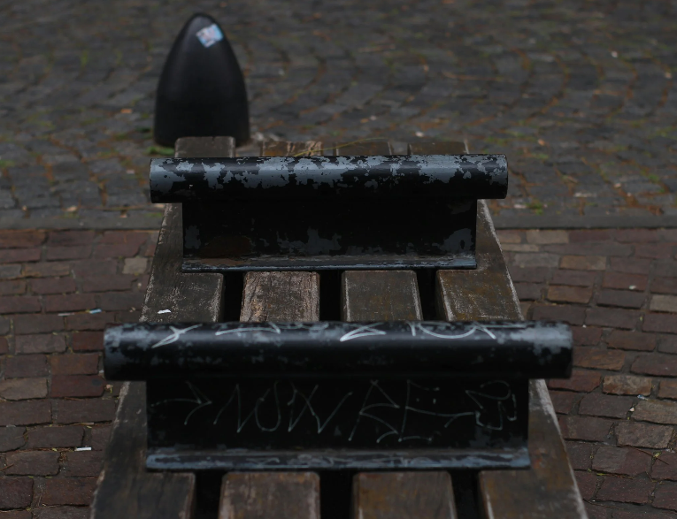 An image of a bench with barriers on the wood