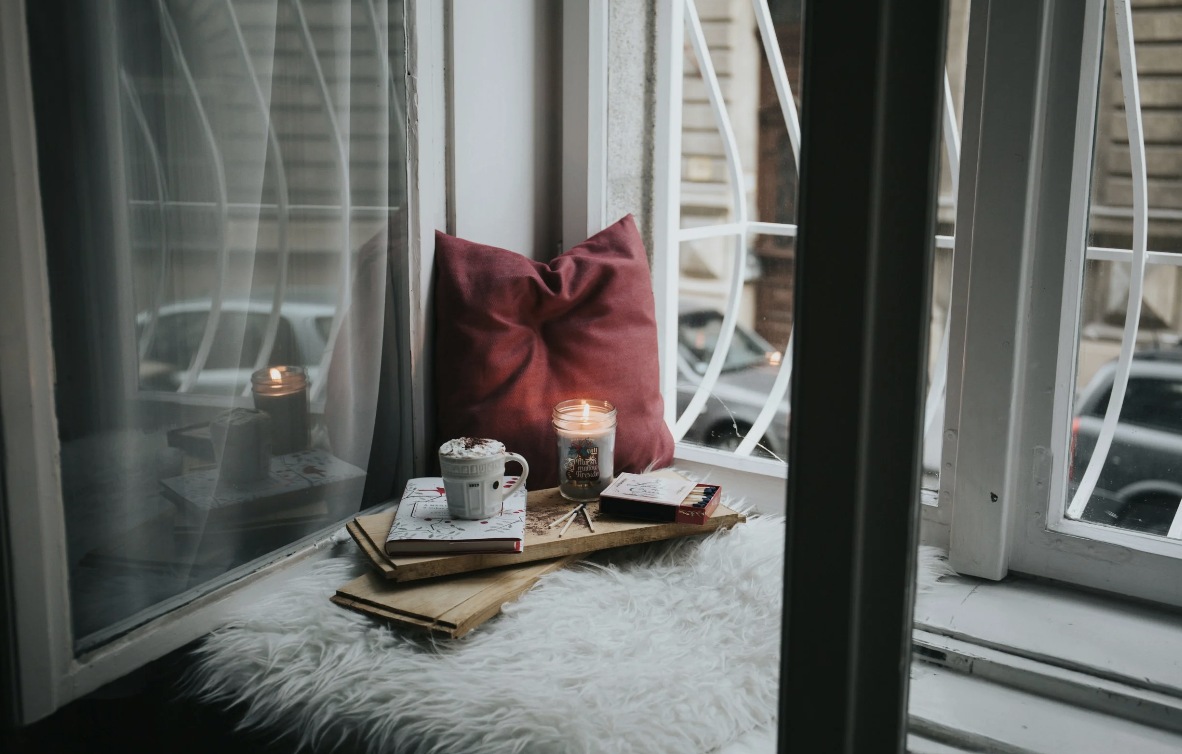 image of a bayside window, with a pillow and tray holding a candle, book, and mug
