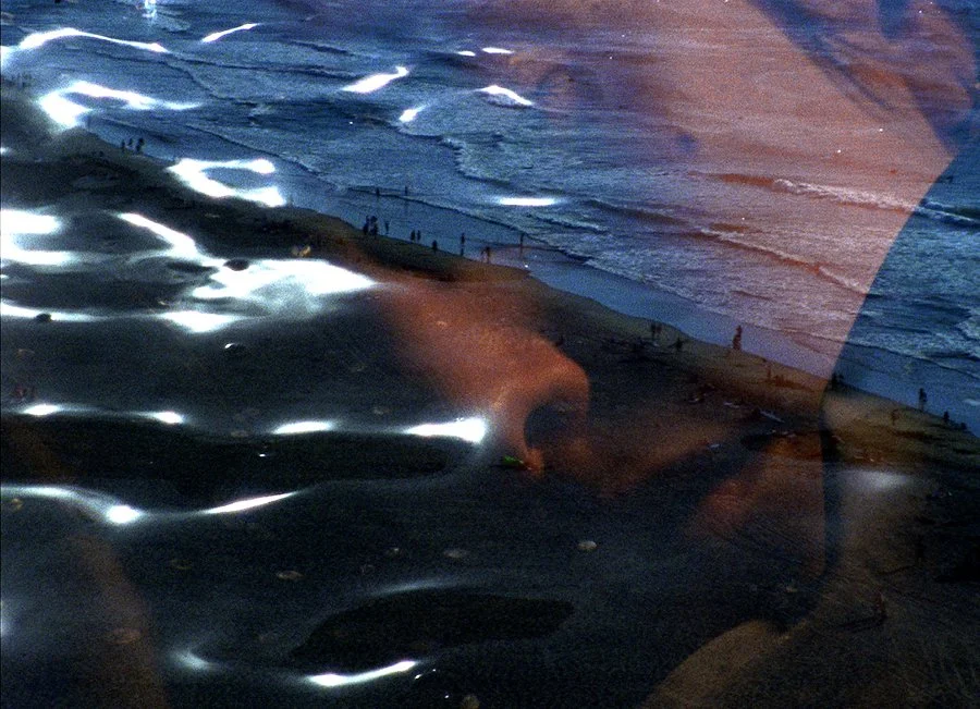 A photo of a beach double exposed with a person's face and water details.