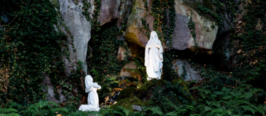 Two statues of Catholic saints in a nature setting