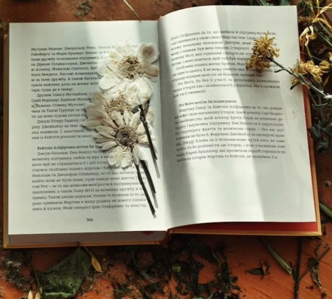 An open book with dried flowers on top.