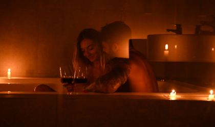 two people getting intimate in a bathtub surrounded by candles