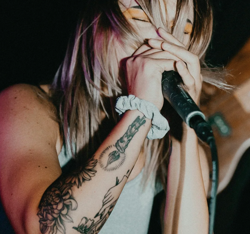 A photo of a person singing, with their hair in their face