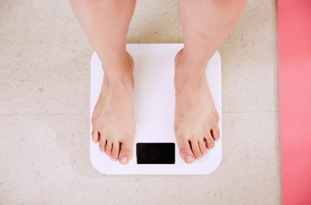 A birds-eye view of a pair of feet on a white weight scale.