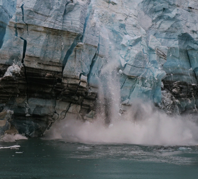 An iceberg melting and falling into the ocean.