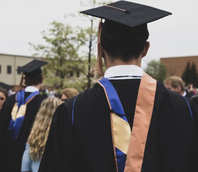 The back of someone who is graduating. They are wearing a black cap and gown