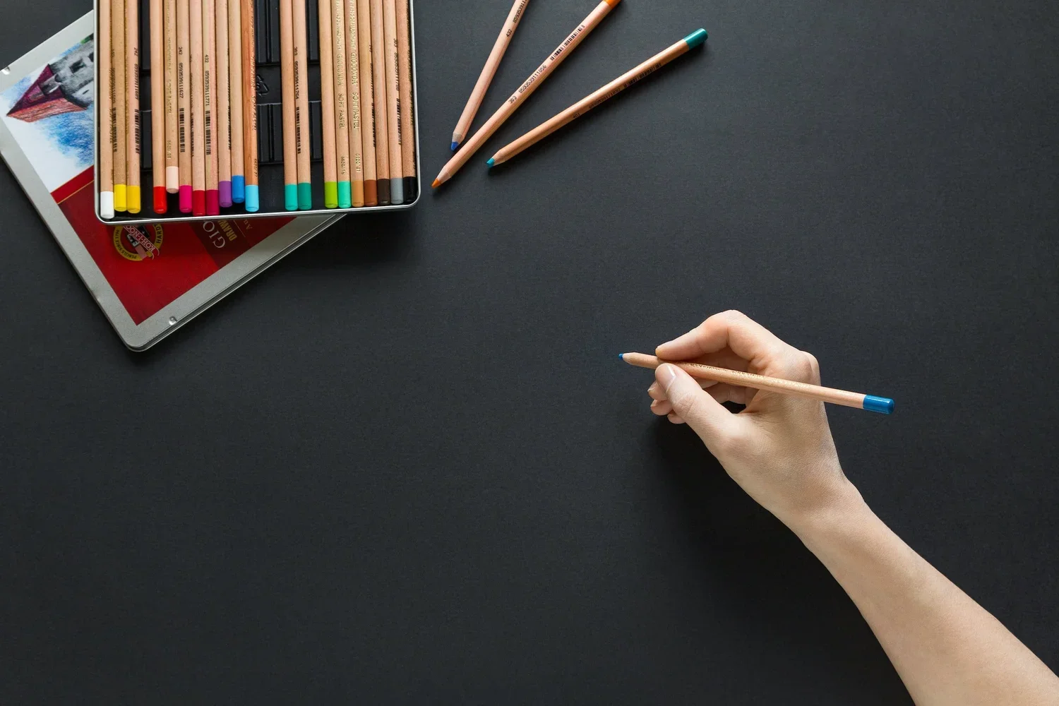 a person's hand holding a pencil in front of a pencil-case
