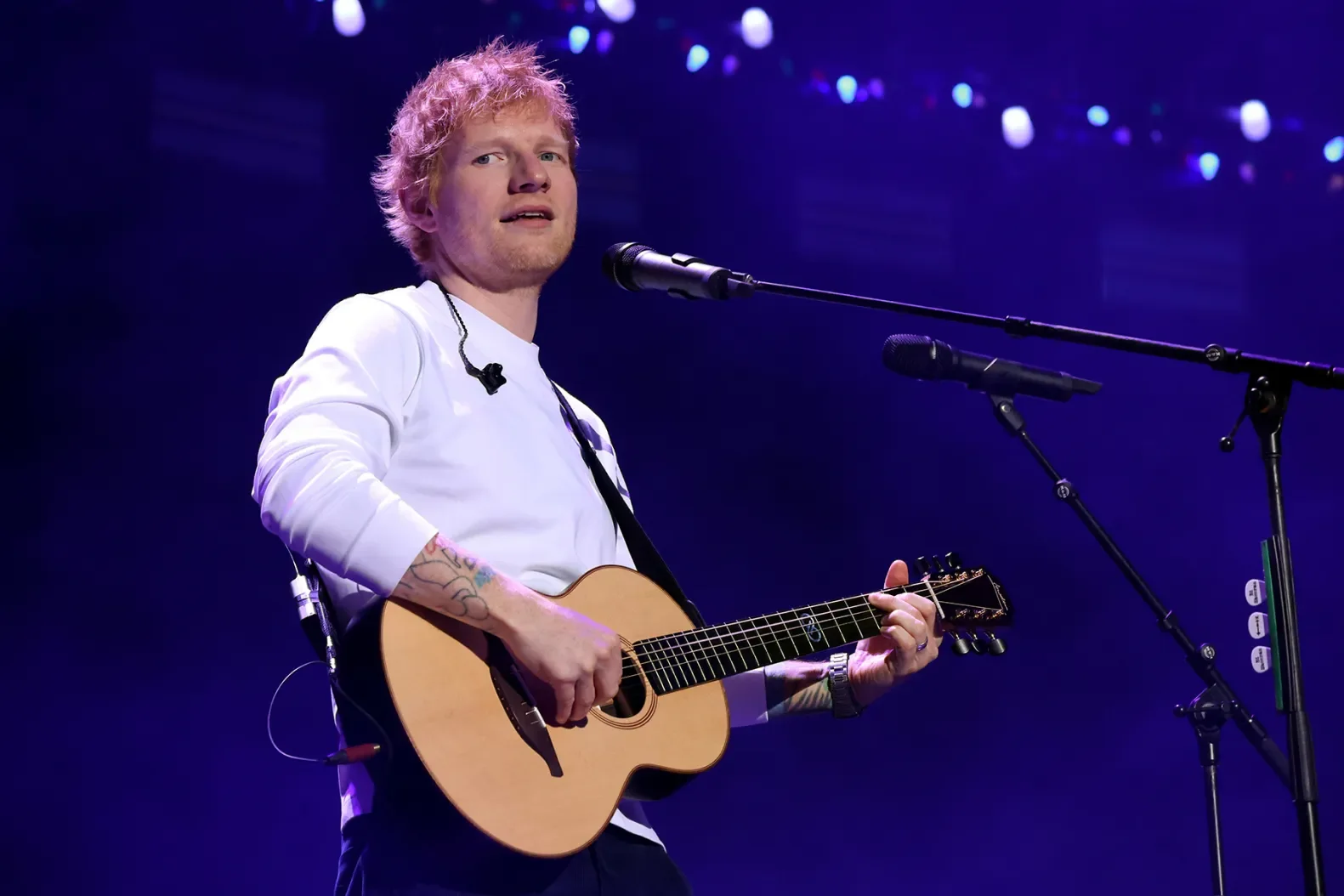 Ed Sheeran holds a guitar on stage during a concert