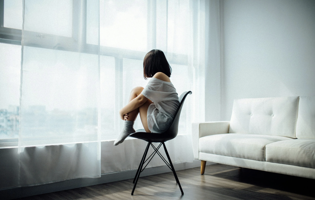 image of woman sitting on a chair looking out a window