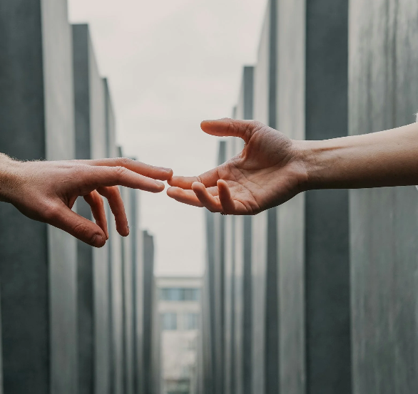 Two hands in front of city buildings reaching towards each other.