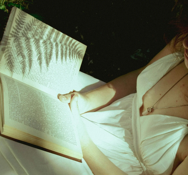 A women in a white dress holding an open book.