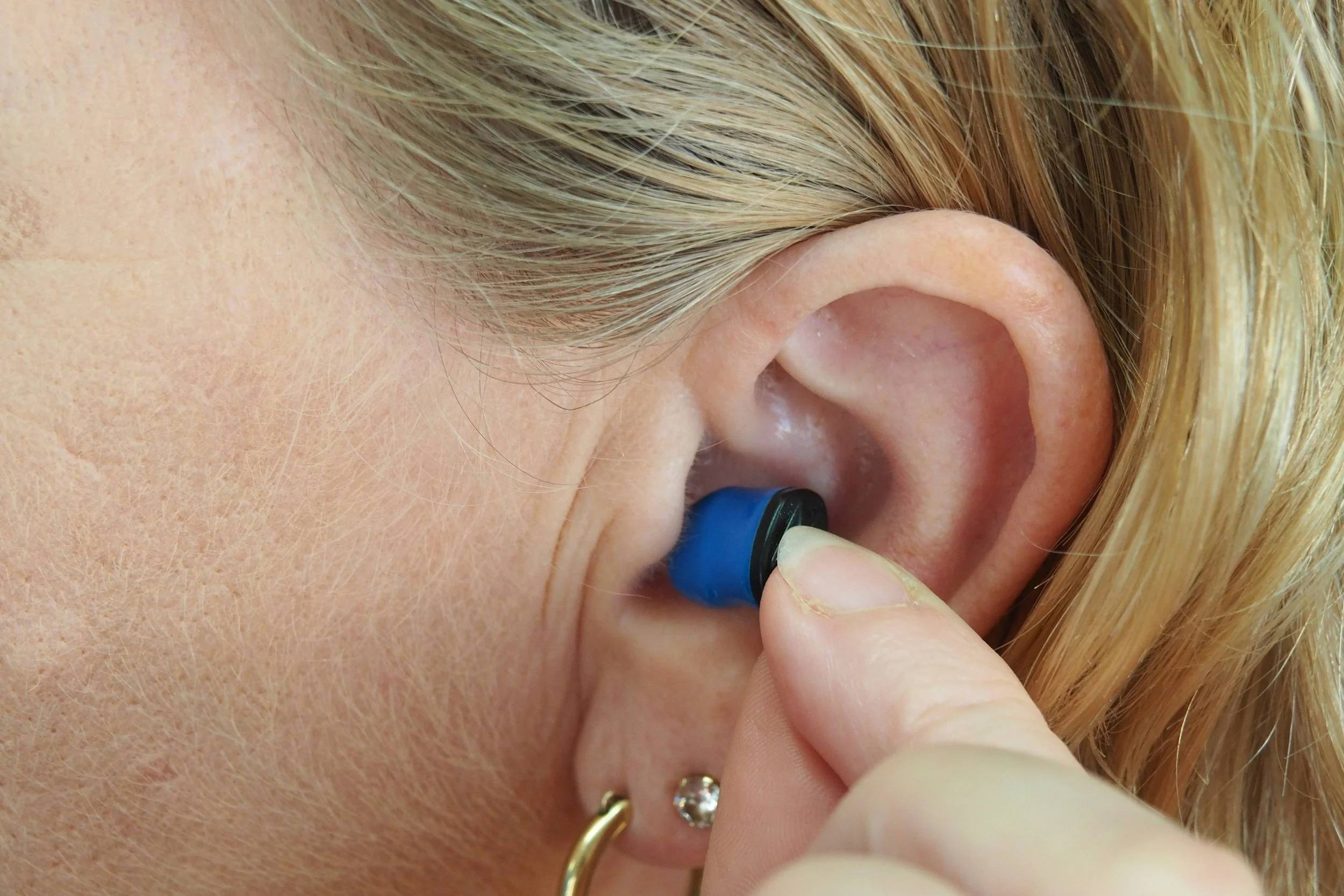 Image of Person putting a blue ear plug into their ear