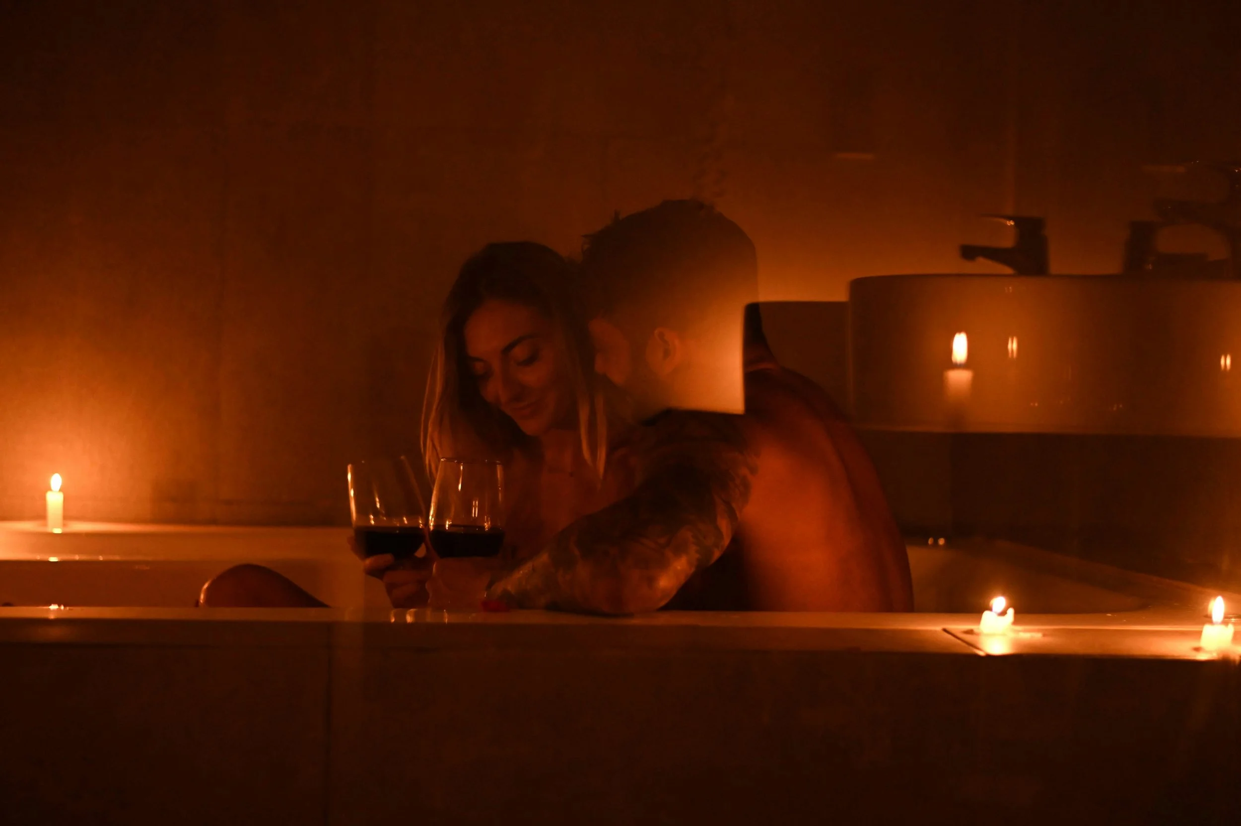 a couple in a bathtub with candles surrounding them