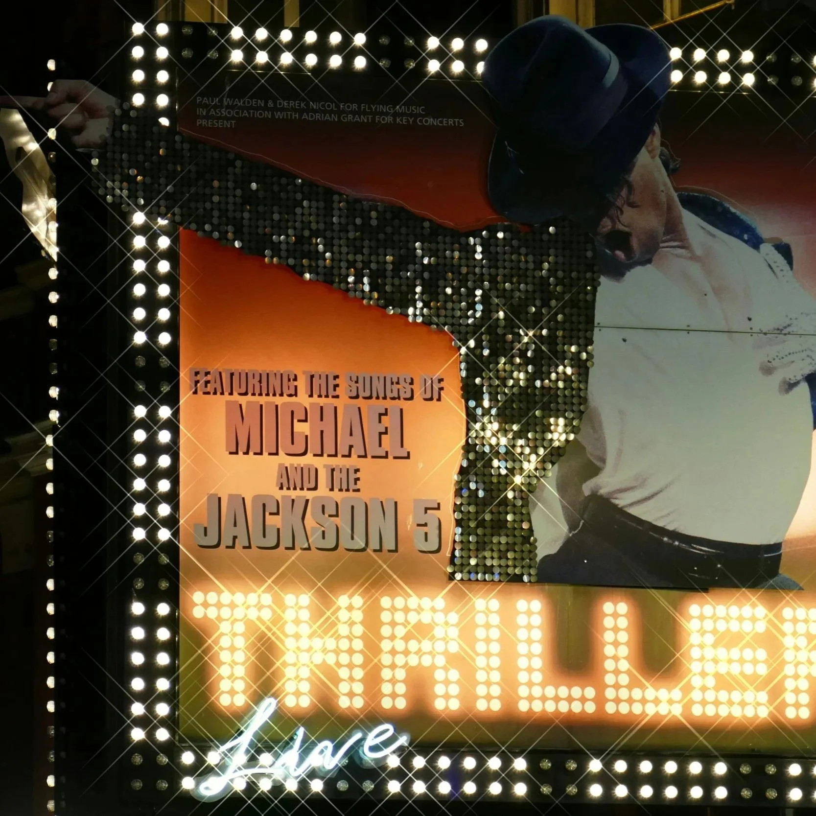 A photo of a theater marquee displaying Michael Jackson. The marquee text reads "Featuring the Songs of Michael and the Jackson 5: Thriller Live."
