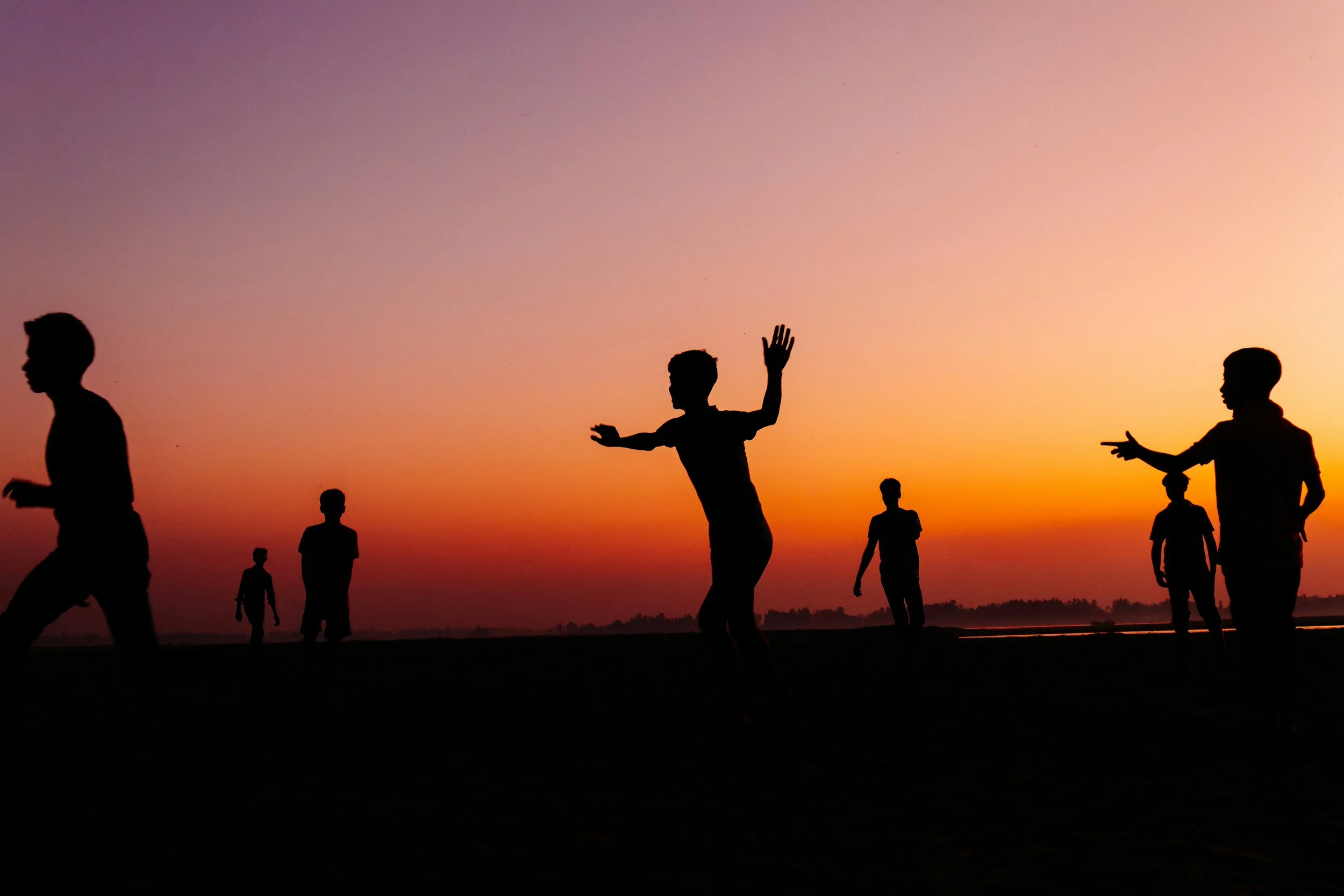 A group of young people running on the beach at sunset