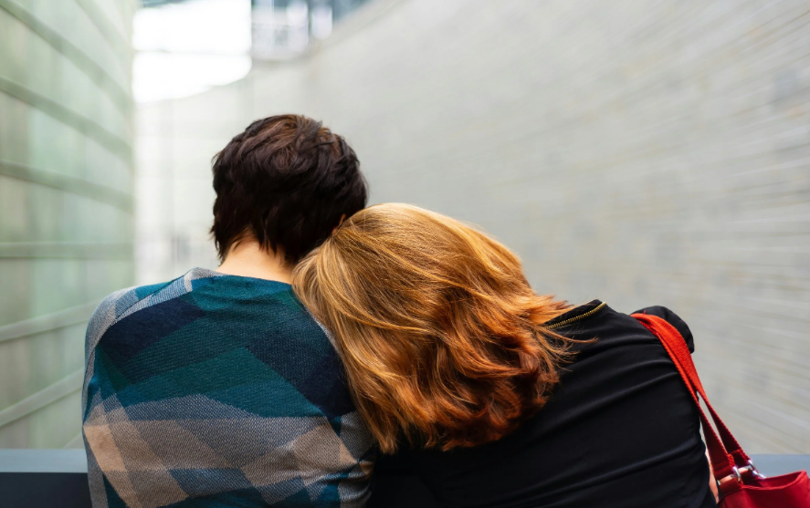 Photo of a one person leaning their head on another persons shoulder