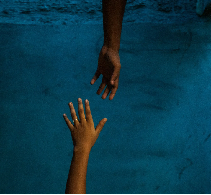 Two hands underwater reaching towards each other.