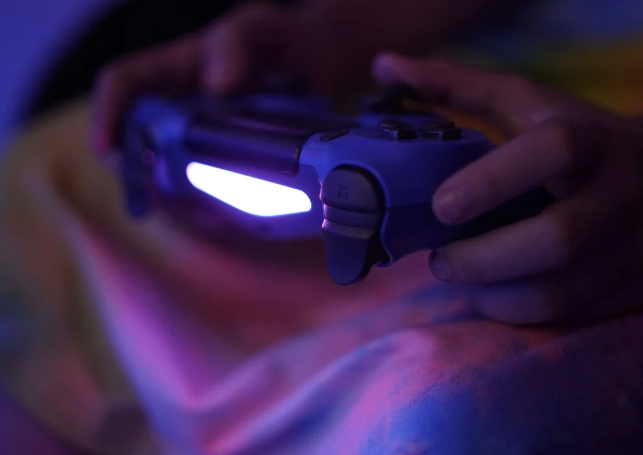 A pair of hands holding a ps4 remote controller.