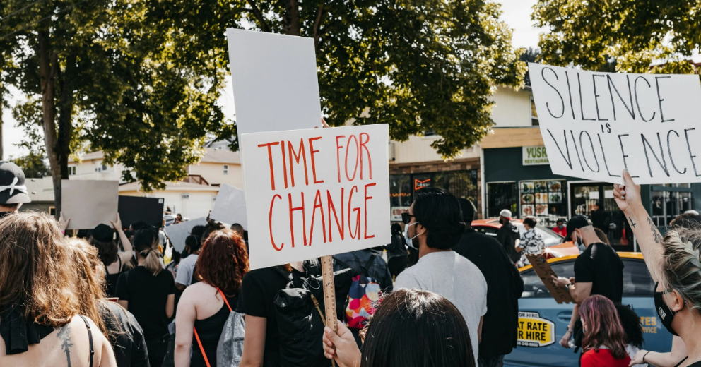Picture of protesters one is holding up a sign that says time for change